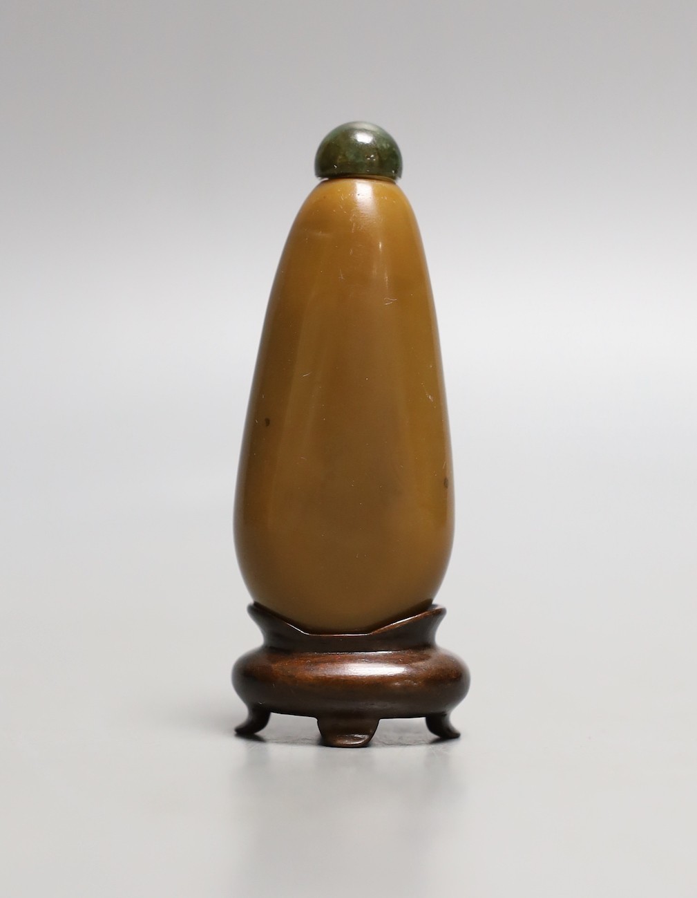 A Chinese brown glass ‘pebble’ snuff bottle in imitation of stone, wood stand